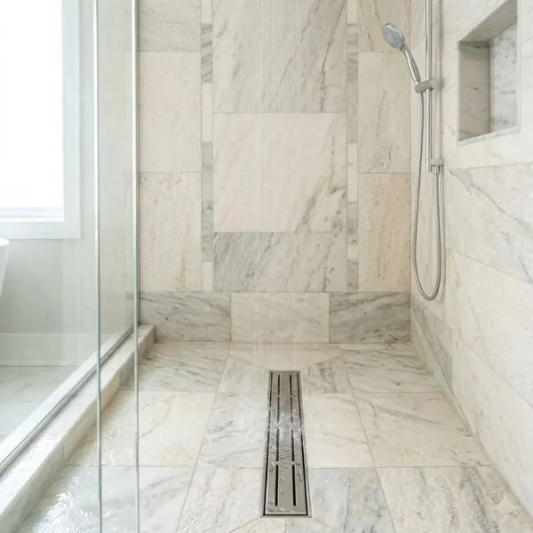 Beautifully tiled walk-in shower floor featuring a spotless modern drain.