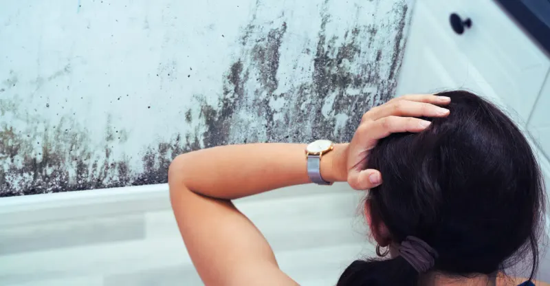 A woman looking at a moldy bathroom