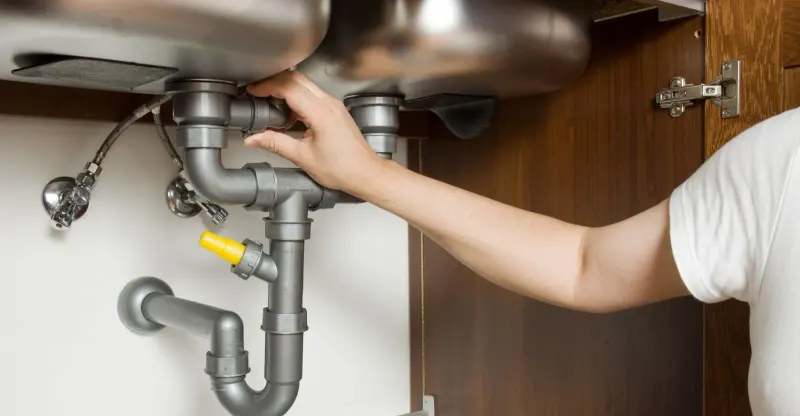 plumber working under sink