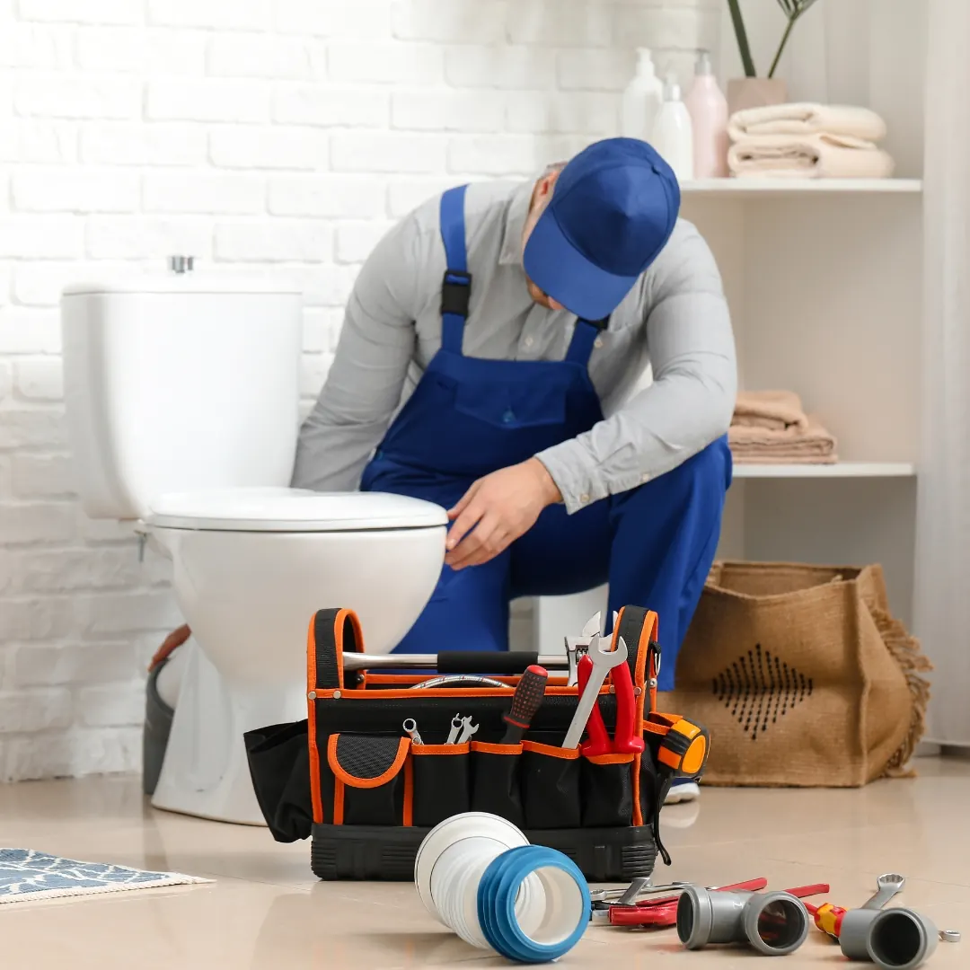 plumber kneels next to toilet