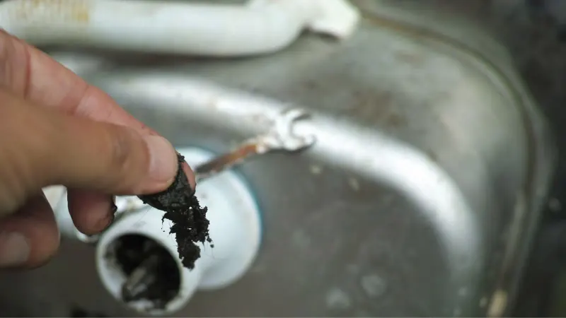 bottom of sink with gunk pulled out of the drain pipe