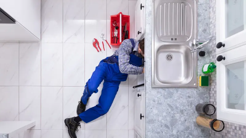 plumber working under kitchen sink