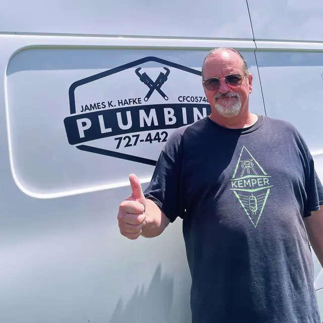 A Hafke Plumbing customer photographed beside a Hafke service van after a completed job