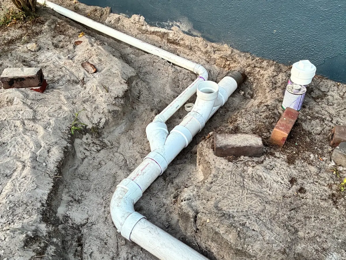New PVC drain line run along a commercial foundation
