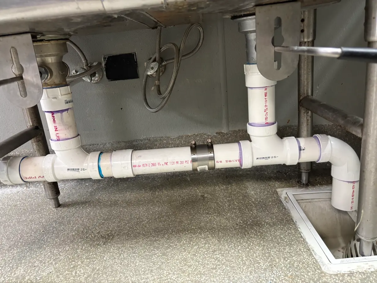Garbage disposal drain and trap connections under a sink