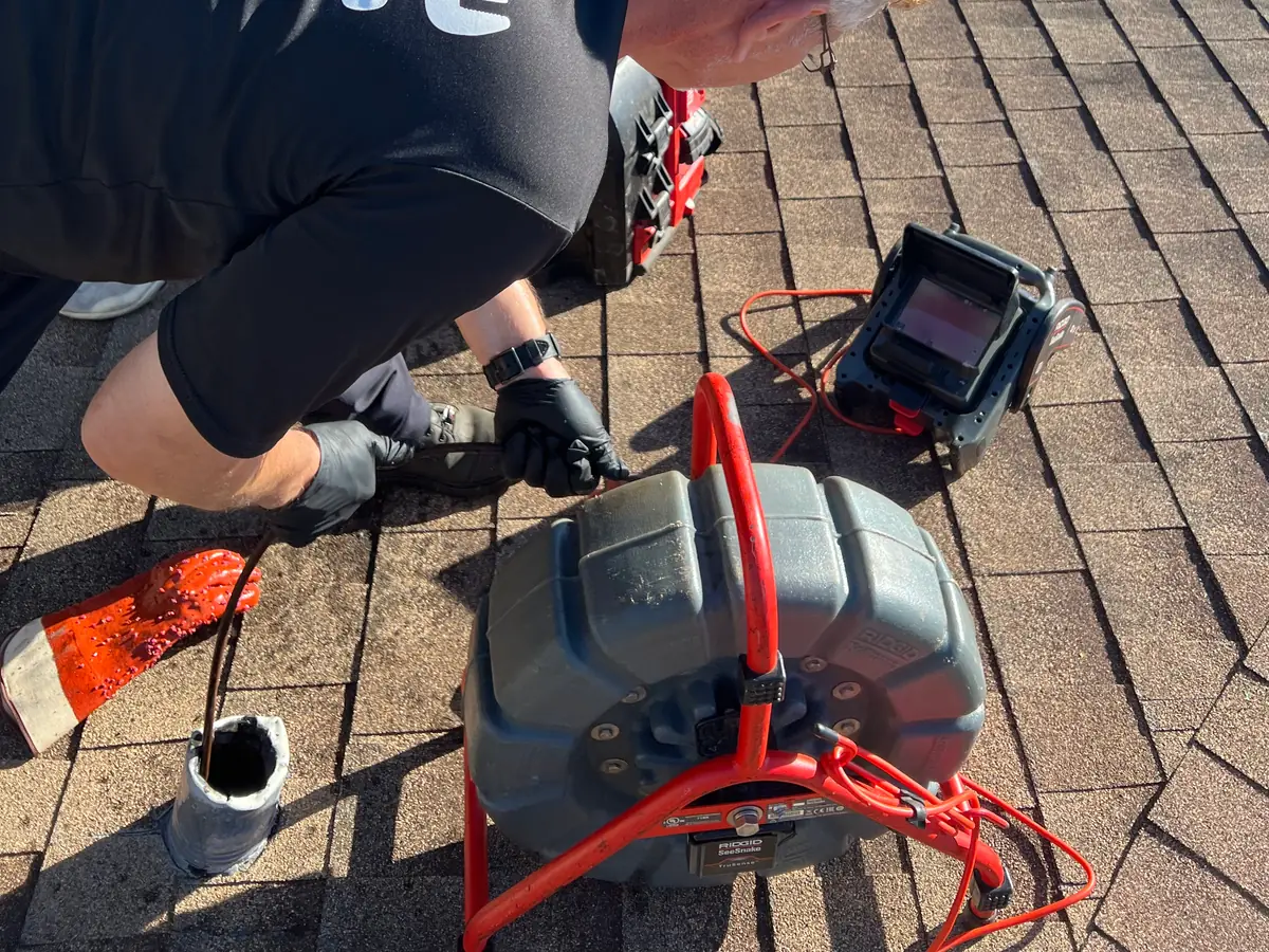 Hafke Plumbing technician running a sewer camera from a roof vent