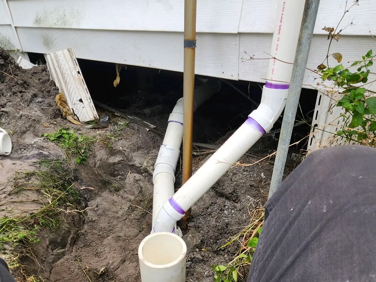 Plumber repairing a drain line beside a slab foundation