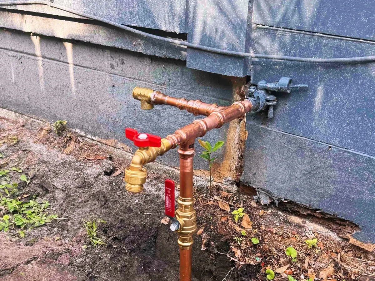 Copper water line and shutoff valves exposed in an open trench
