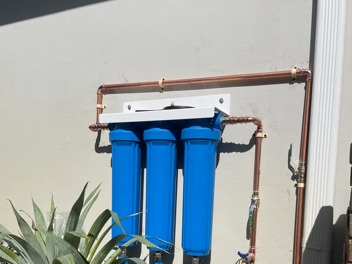 Three-stage water filtration system mounted on an exterior wall