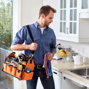 plumber observing sink while holding toolbox