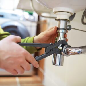 plumber works on drain with a wrench 