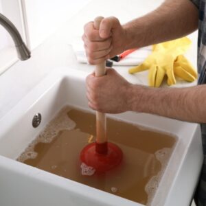 Man plunging dirty sink with standing water