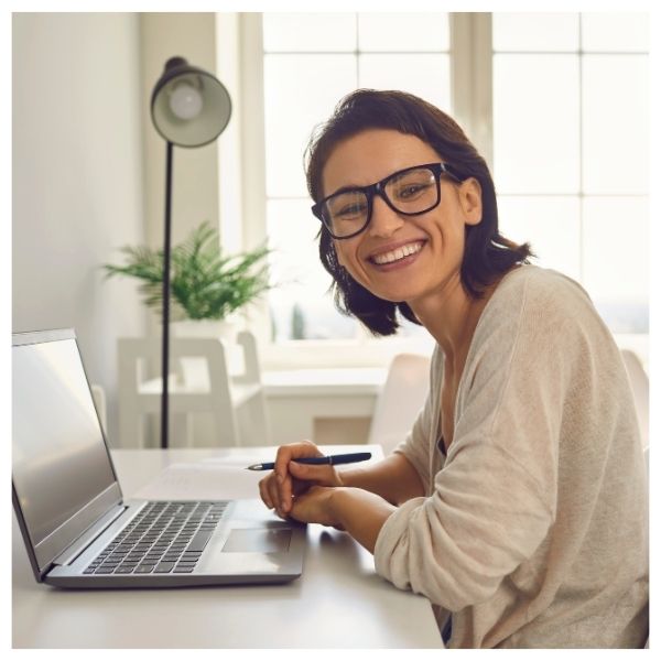 smiling woman looking up from laptop