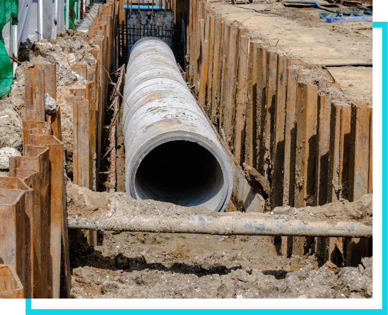 Large-scale commercial sewer main installation featuring high-capacity concrete piping in a shored trench.