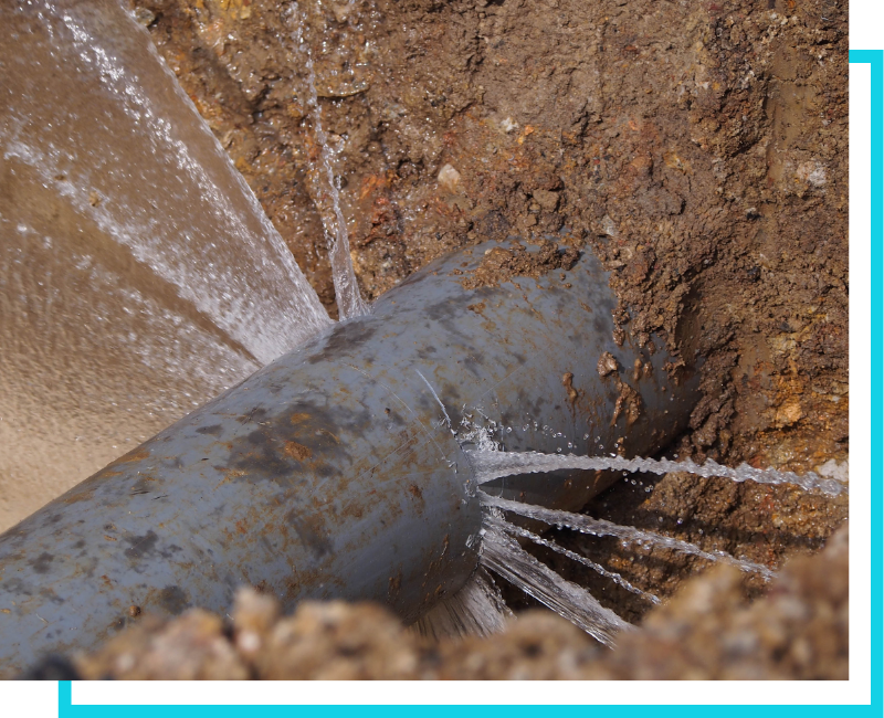 A major sewer main line break spraying water in a trench, requiring emergency commercial repair services.